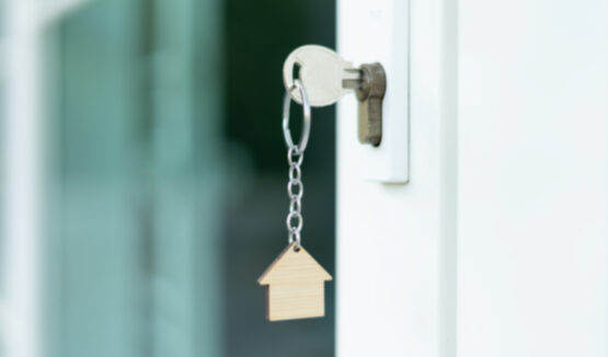 Llave en una puerta con llavero con forma de casa.