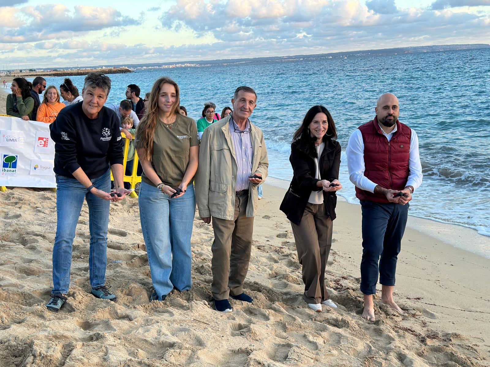 Grup de gent alliberant tortugues a la platja