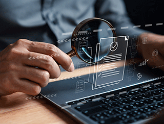 Mà amb una lupa sobre un ordinador