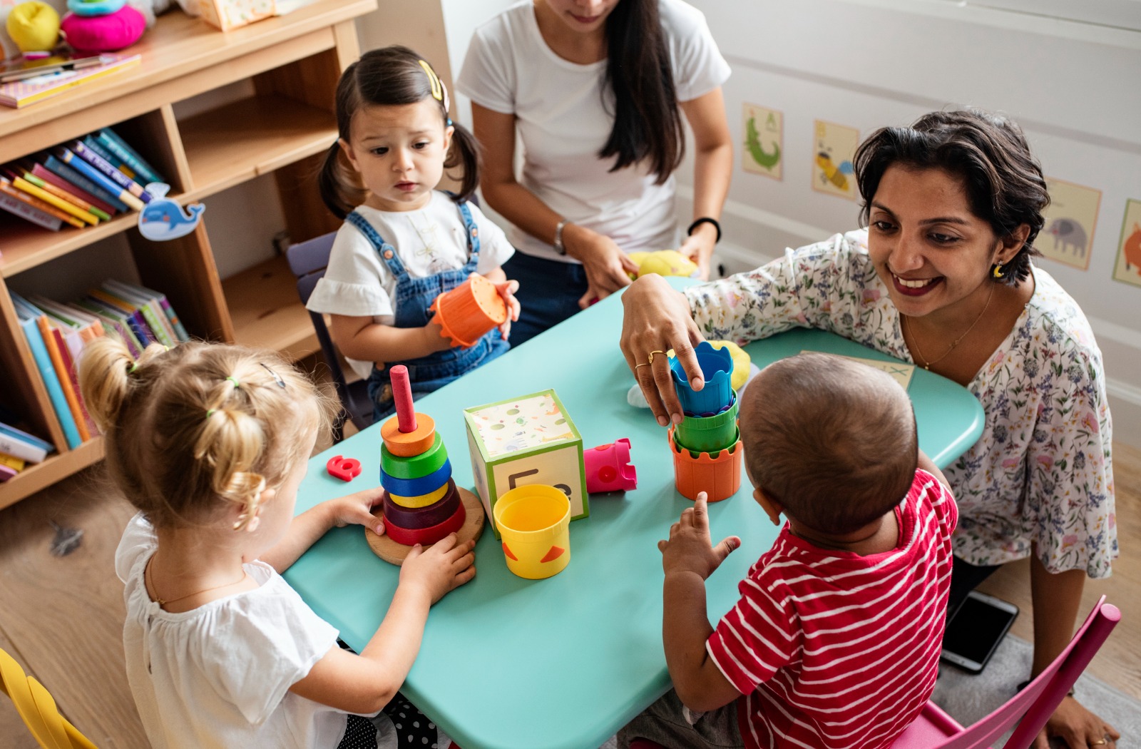 Un grup d'infants juguen amb una professora a una escoleta.