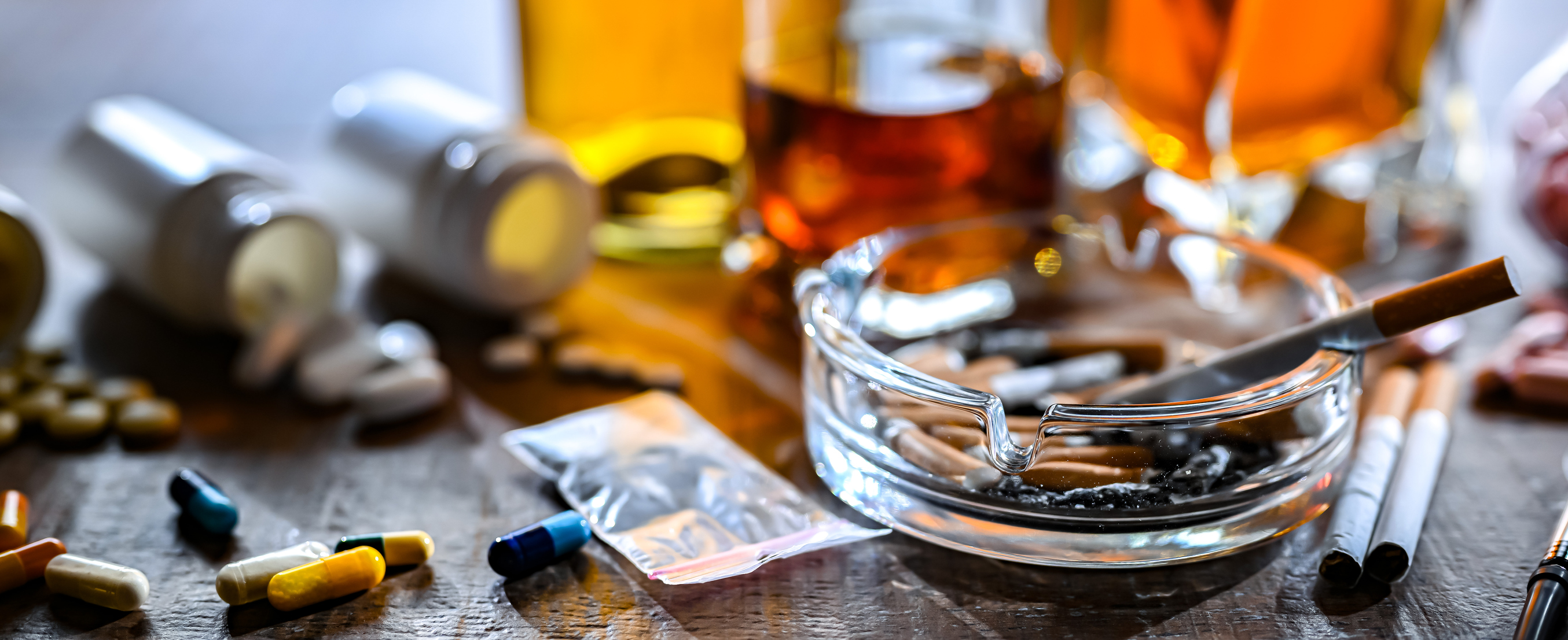 Pastilles, botelles d'alcohol i cigarrets damunt una taula.