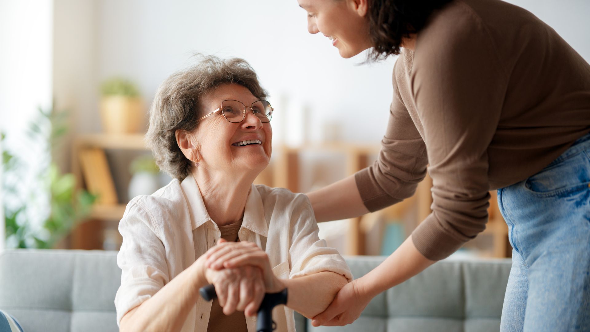 Una jove atèn una dona major amb bastó.