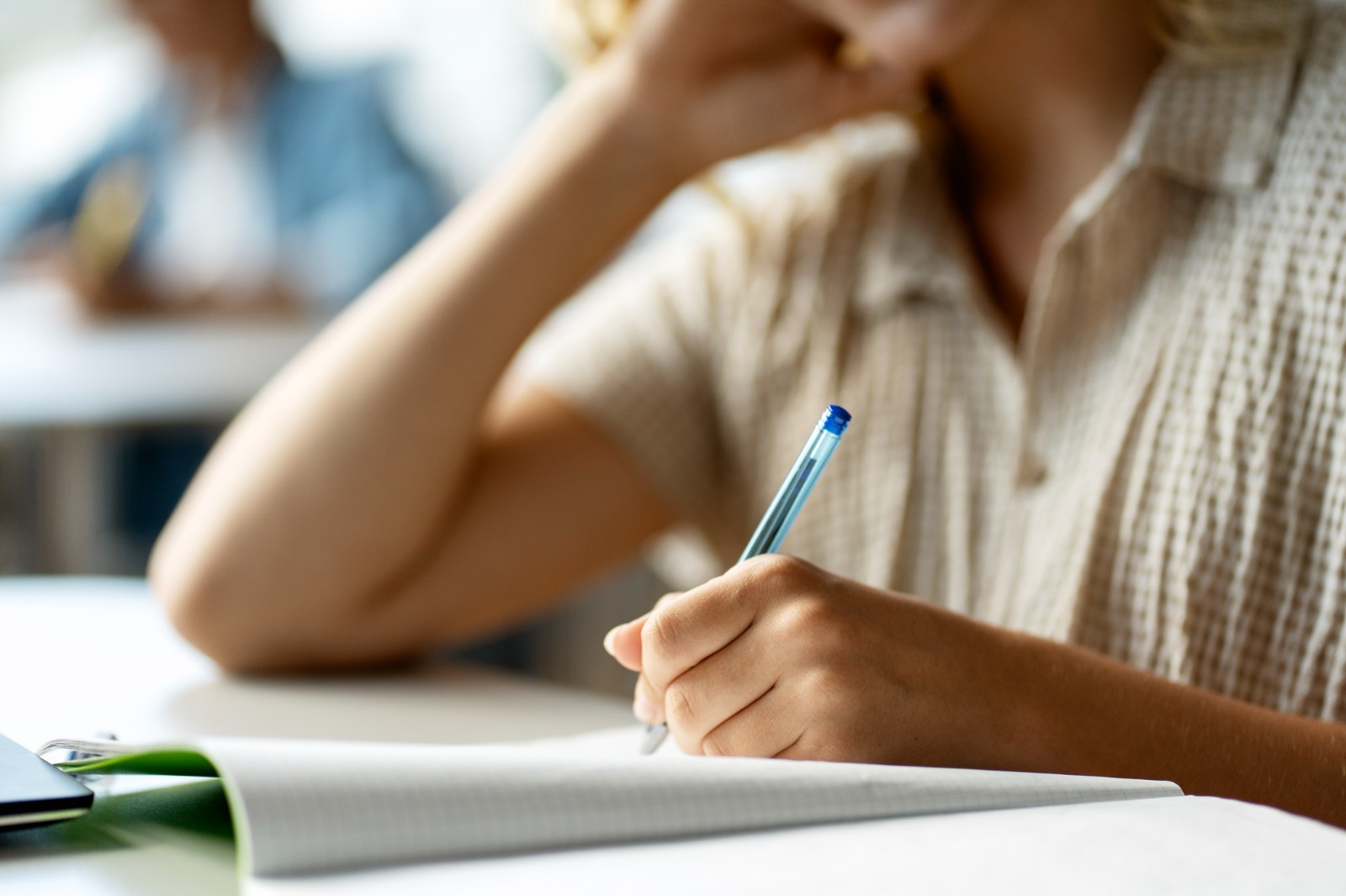 Un alumne en una aula escriu en un quadern. Un alumne en una aula escriu en un quadern.