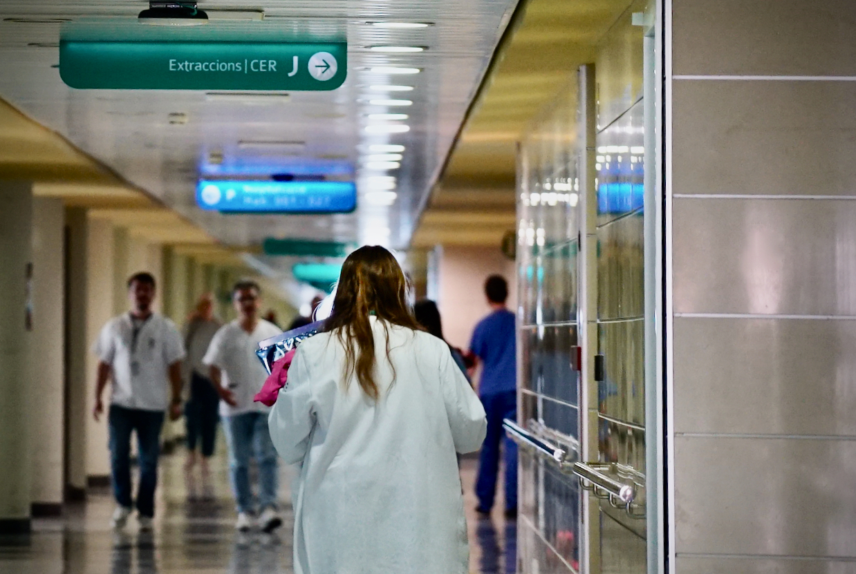 Passadís d'hospital amb una professional sanitària que camina. 