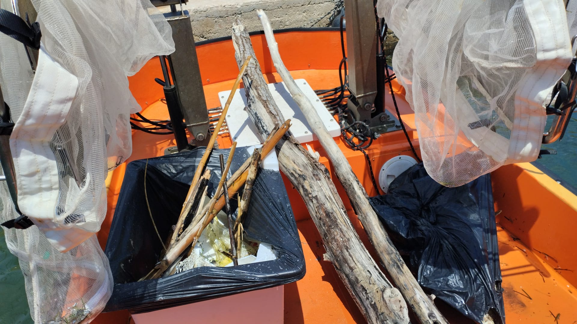 Embarcació amb xarxes, restes de fusta i altres residus del mar.