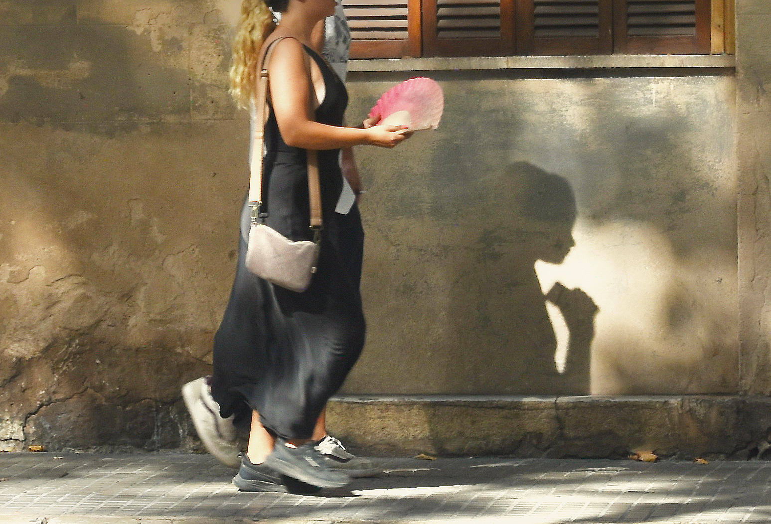 Una ciutadana camina amb un ventall a la mà. 